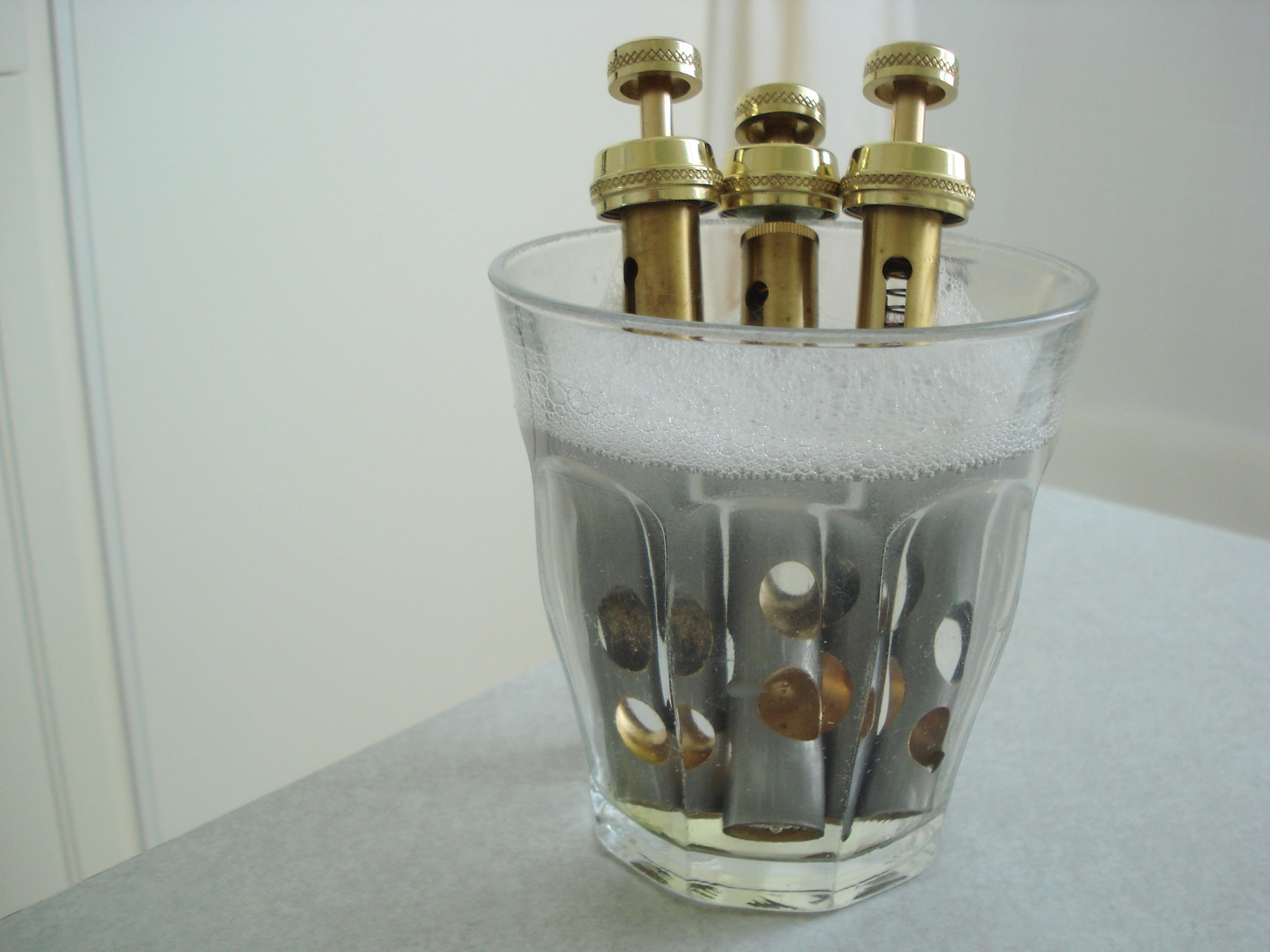 Trumpet valves soaking in a glass of soapy water